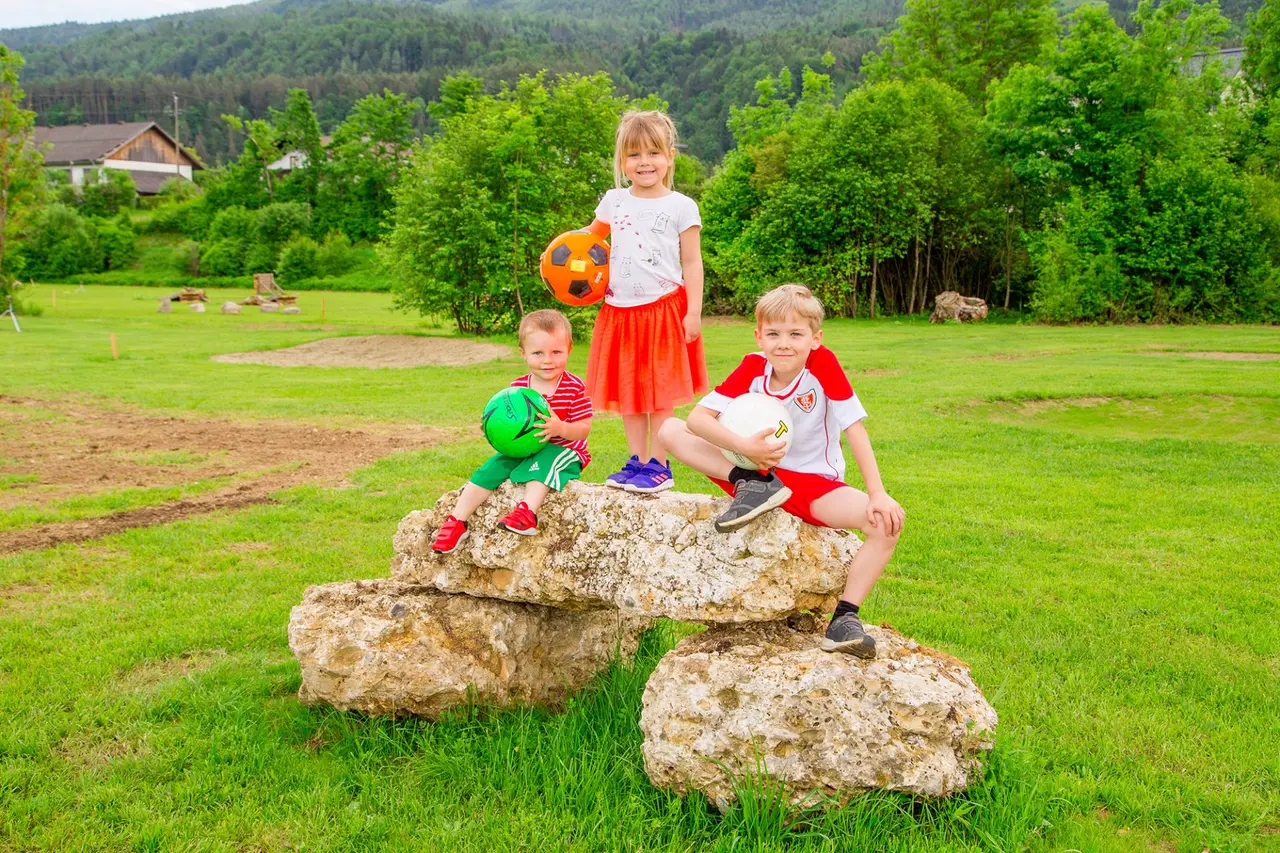 Eine Gruppe von drei Kindern mit Fußbällen auf der Kick2Gether-Anlage