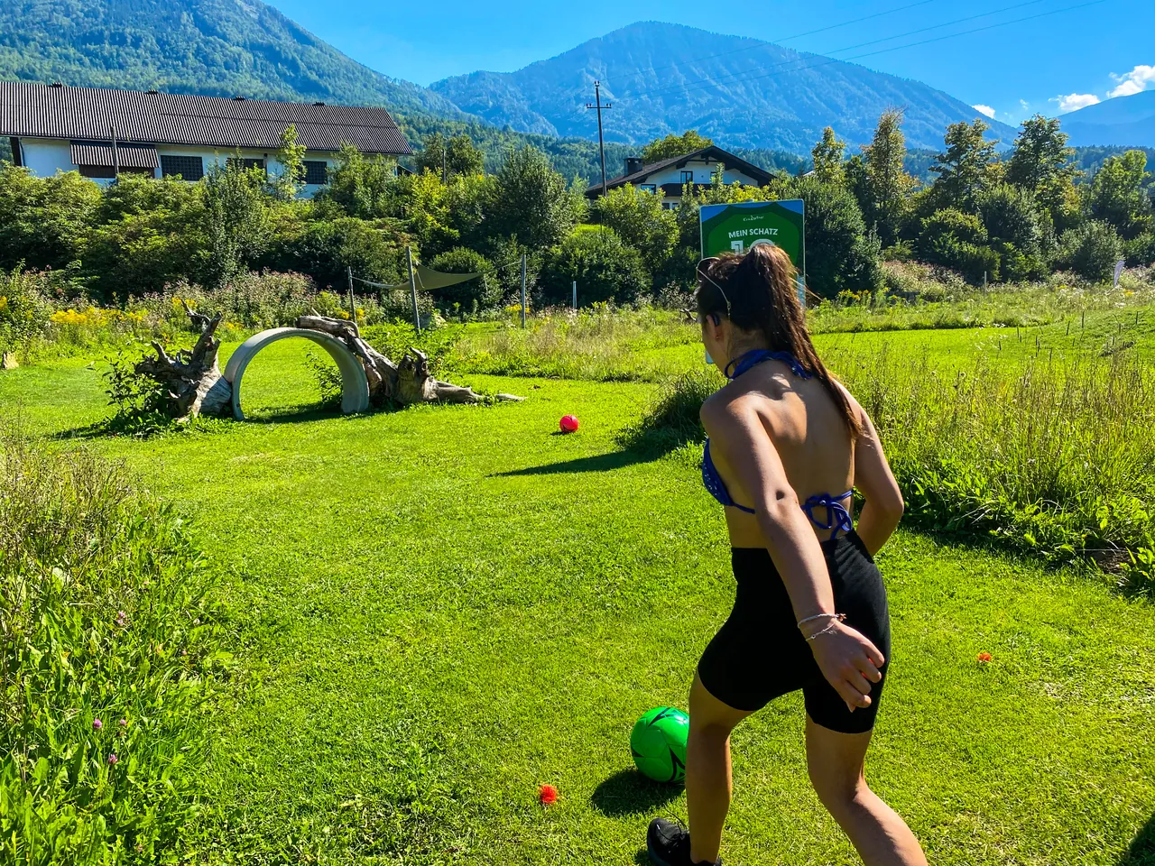 Eine Spielerin kickt einen grünen Fußball in Richtung Ringhindernis